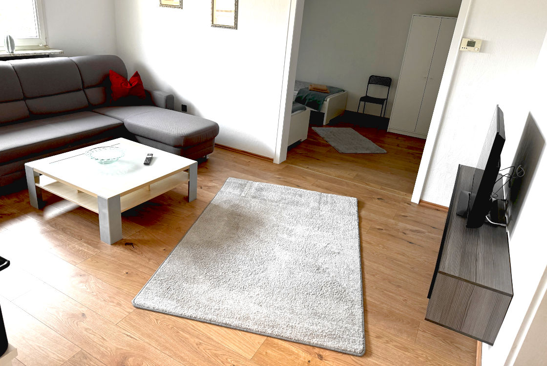 Wohnzimmer der 4-Zimmer-Wohnung RS07 in Remscheid mit Sofa, TV und Sitzecke.